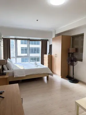 a hotel room with a bed and a large window at StayHere BGC City Studio in SOMA near SM Aura in Manila