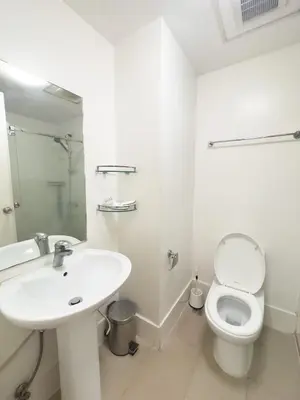a white bathroom with a sink and a toilet at StayHere BGC City Studio in SOMA near SM Aura in Manila