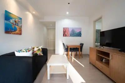 a living room with a black couch and a tv at StayHere BGC City Studio in SOMA near SM Aura in Manila