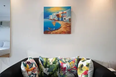 a painting hanging on a wall above a couch at StayHere BGC City Studio in SOMA near SM Aura in Manila