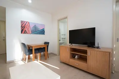 a living room with a tv and a wooden cabinet with a table at StayHere BGC City Studio in SOMA near SM Aura in Manila