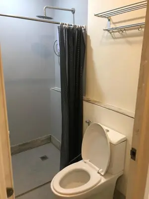 a bathroom with a toilet and a black shower curtain at One Biñan Place in Biñan