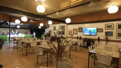 a dining room with tables and chairs and a tv at Loreland Farm Resort in Antipolo