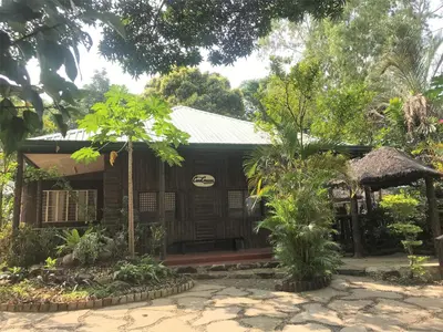 a small wooden house with a porch and trees at Loreland Farm Resort in Antipolo
