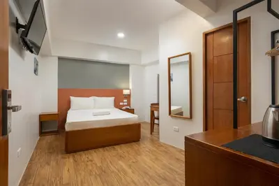a bedroom with a bed and a desk and a mirror at iHotel Uptown BGC in Taguig
