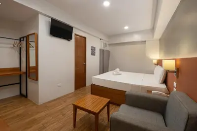 a small hotel room with a bed and a couch at iHotel Uptown BGC in Taguig