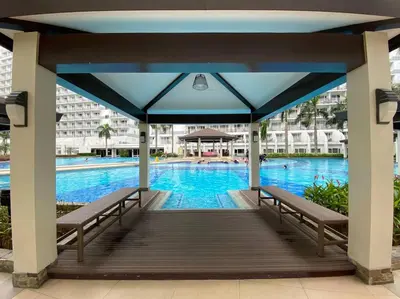 a gazebo with benches next to a swimming pool at Cozy Space at Shell Residences in Tower A in Manila
