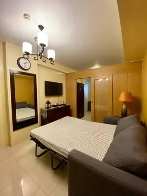 a living room with a bed and a mirror at Cozy Space at Shell Residences in Tower A in Manila