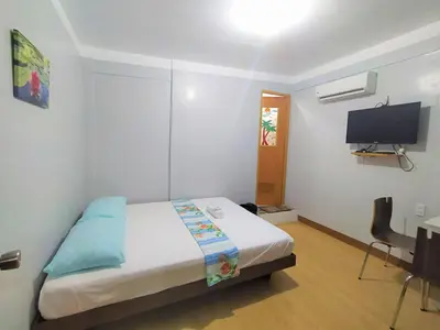 a bedroom with a bed and a desk and a television at JB Valdres Apartment in Manila