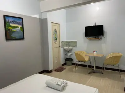 a room with a bed and a table and a tv at JB Valdres Apartment in Manila