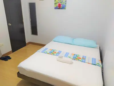 a white bed with blue pillows on top of it at JB Valdres Apartment in Manila