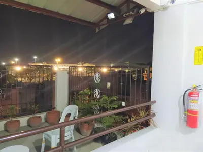 a balcony with two white chairs and plants at night at JB Valdres Apartment in Manila