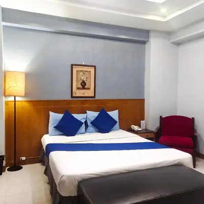 a hotel room with a bed and a red chair at Alley 8 Makati in Manila