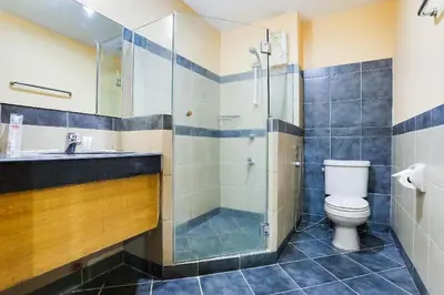 a bathroom with a shower and a toilet and a sink at Alley 8 Makati in Manila