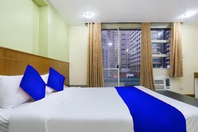 a bedroom with a large bed with blue pillows and a window at Alley 8 Makati in Manila