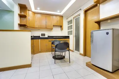 a kitchen with wooden cabinets and a white refrigerator at Alley 8 Makati in Manila