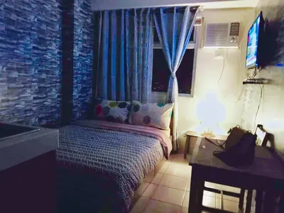 a bedroom with a bed and a window and a table at Booker Com in Mandaluyong in Manila