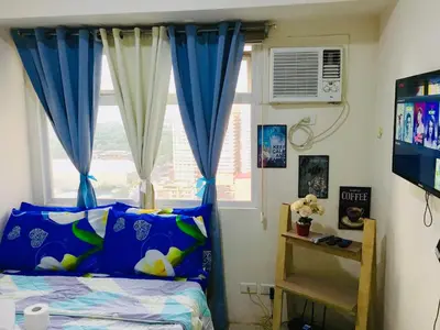 a bedroom with a bed and a window with blue curtains at Booker Com in Mandaluyong in Manila