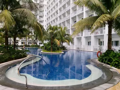 a large swimming pool with palm trees in front of a building at Tower C Shore Residences by CSLUXE in Manila