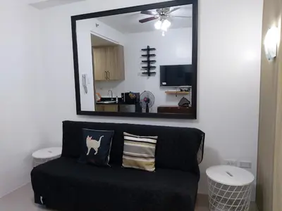 a black couch in a living room with a mirror at Tower C Shore Residences by CSLUXE in Manila