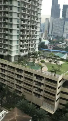 a view of a large building with palm trees on it at Makati CBD Resort 2 bedroom in Manila