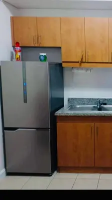 a kitchen with a stainless steel refrigerator and wooden cabinets at Makati CBD Resort 2 bedroom in Manila