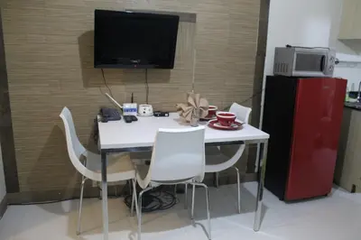 a kitchen with a table with white chairs and a tv at Chateau Elysee a14 near Airport Wifi Kitchen in Manila