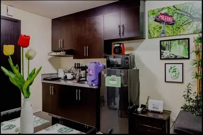 a kitchen with wooden cabinets and a refrigerator at A Refreshing Condo Unit Near BGC, Ortigas & Makati with NETFLIX and WiFi in Manila