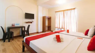 a room with two beds and a desk and a television at RedDoorz Plus near Johnson and Johnson Paranaque in Manila