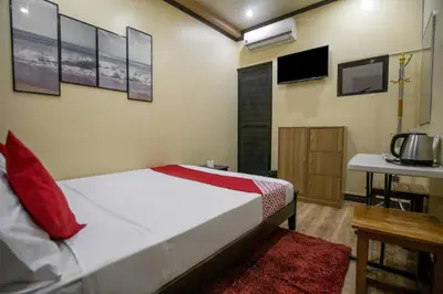 a bedroom with a bed and a table and a tv at Rjat Guesthouse in Biñan
