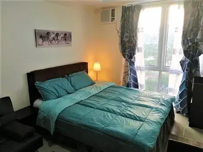 a bedroom with a bed and a window at Studio Condominium - Short and Long Term Staycation in Manila