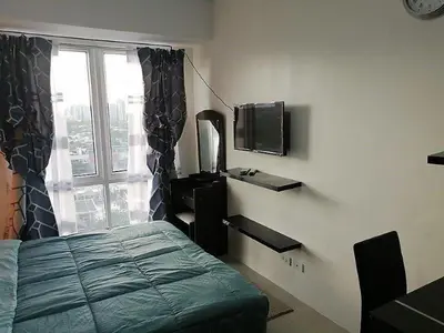a bedroom with a bed and a tv and a window at Studio Condominium - Short and Long Term Staycation in Manila