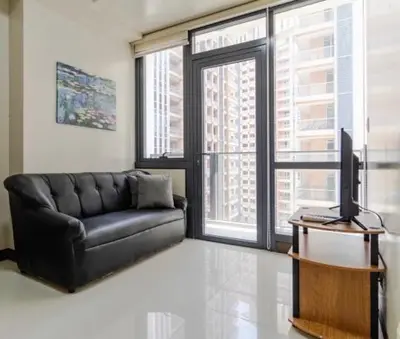 a living room with a black couch and a television at Madisons Crib at The Florence in Manila
