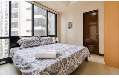 a bedroom with a bed with a large window at Madisons Crib at The Florence in Manila