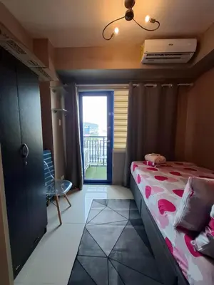 a bedroom with a bed and a window with a balcony at King of kings at SEA RESIDENCES in Manila