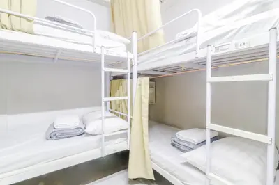 a bunk bed room with white bunk beds and towels at ARK Hostel City Center Manila in Manila