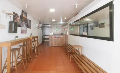 a bar with wooden stools and a mirror on the wall at RedDoorz near OWWA Pasay in Manila