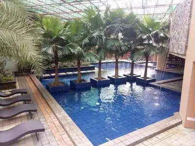a large swimming pool with palm trees in a building at U607 Sunshine100 Netflix 65InchesTV Wifi Karaoke Swimming Pool in Manila