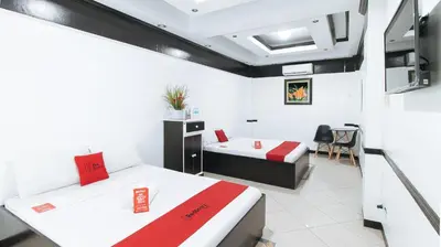 a room with two beds and a table in it at RedDoorz Plus at Villa Gloria Taguig in Manila