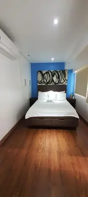 a bedroom with a large bed with a wooden floor at BGC Fort Victoria in Manila