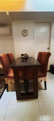 a dining room table with chairs and a clock on the wall at BGC Fort Victoria in Manila