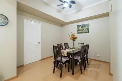 a dining room with a table with chairs and a ceiling fan at StayHere Burgos Circle 1 Bedroom Avant@Fort Gym in Manila