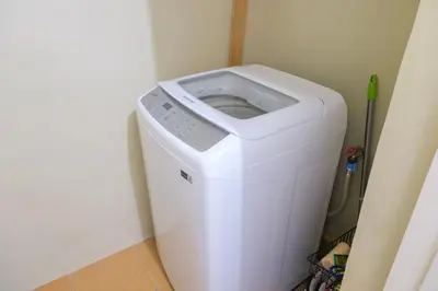 a white washing machine in a corner of a room at StayHere Burgos Circle 1 Bedroom Avant@Fort Gym in Manila