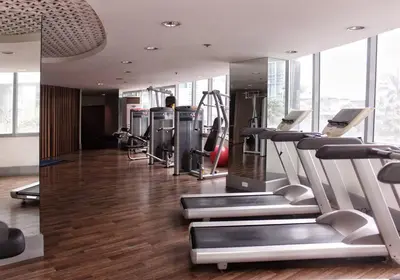 a gym with treadmills and machines in a room at StayHere Burgos Circle 1 Bedroom Avant@Fort Gym in Manila