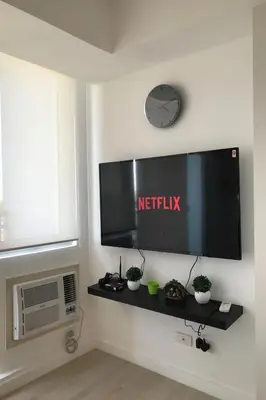 a flat screen tv on a wall with a clock at 1217 Urban Simplicity in Manila
