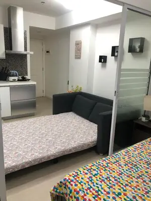 a room with a bed and a couch and a kitchen at 1217 Urban Simplicity in Manila
