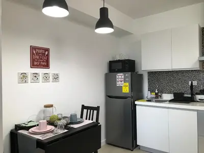 a kitchen with a refrigerator and a counter with a table at 1217 Urban Simplicity in Manila