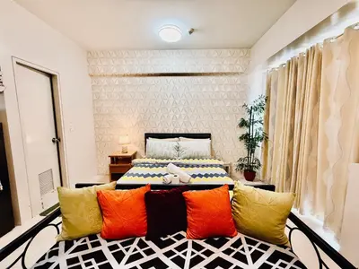 a bedroom with a large bed with colorful pillows at Apartments across NAIA Terminal 3 in Manila