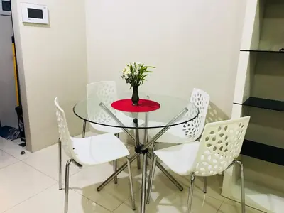 a glass table with white chairs and a vase with flowers at Apartments across NAIA Terminal 3 in Manila