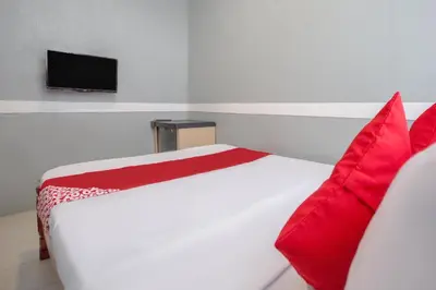 a bedroom with a bed with red pillows and a tv at OYO 588 Sunrock Resort in Antipolo
